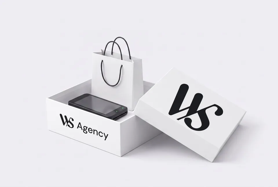 Une boîte blanche WS Agency ouverte, un sac de boutique et un terminal de paiement dedans