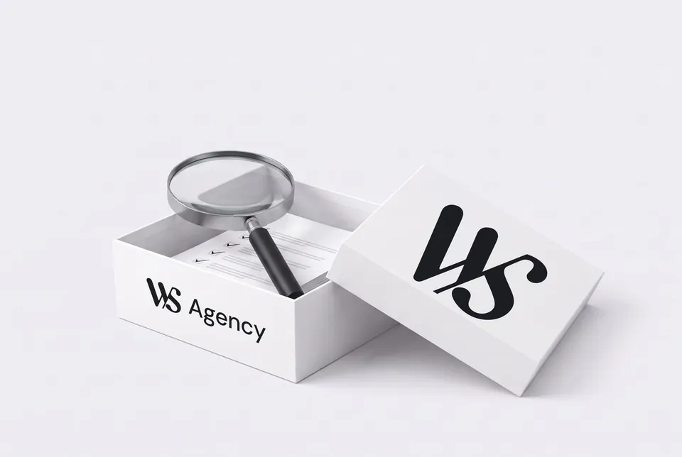 Une boîte blanche WS Agency ouverte, une loupe posée sur un rapport dedans