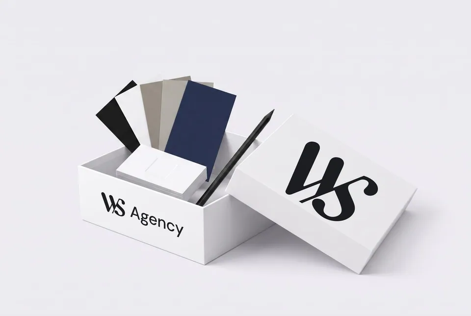 Une boîte blanche WS Agency ouverte, des nuanciers, des cartes de visite et un crayon dedans